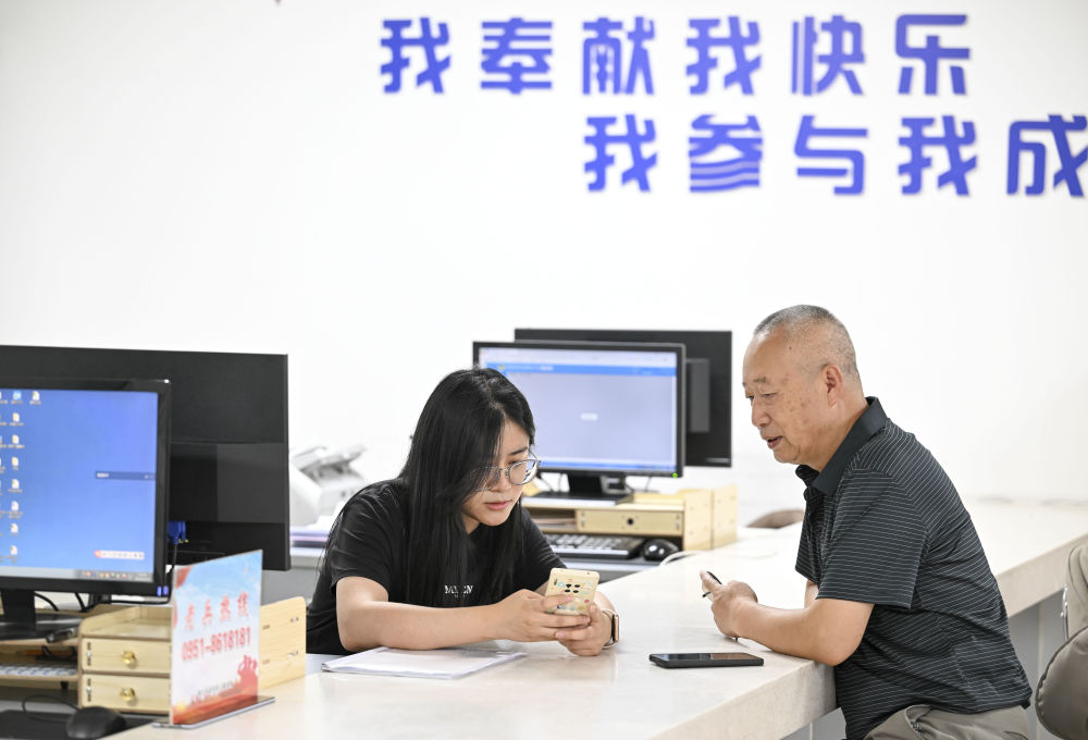 2024年6月20日，在寧夏銀川市金鳳區(qū)長(zhǎng)城花園社區(qū)黨群服務(wù)中心，工作人員幫助居民辦理業(yè)務(wù)。圖片來(lái)源 新華社